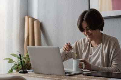 Woman taking CBD oil in tea cup while working at home office. What is CBD? What is CBD good for?